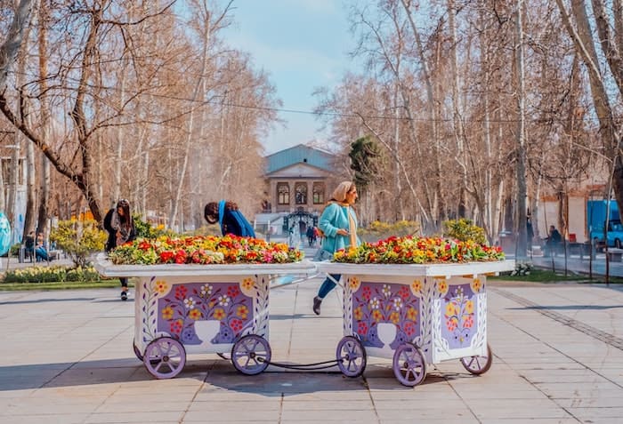two girls behind bunch of flowers in Park Iran-min