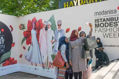 Young women taking a selfie at the entrance of Istanbul Modest Fashion Week, the first International fashion event showcasing collections for Muslim women from across the globe (MEE/Emanuele Satolli)