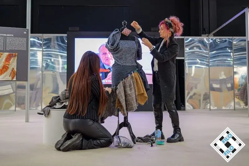 wo women working on a textile art piece displayed on a mannequin at filo exhibition